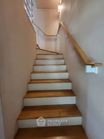 Modern staircase with wooden steps and sleek handrail in a contemporary home