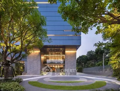 Modern building entrance with lush greenery and circular driveway