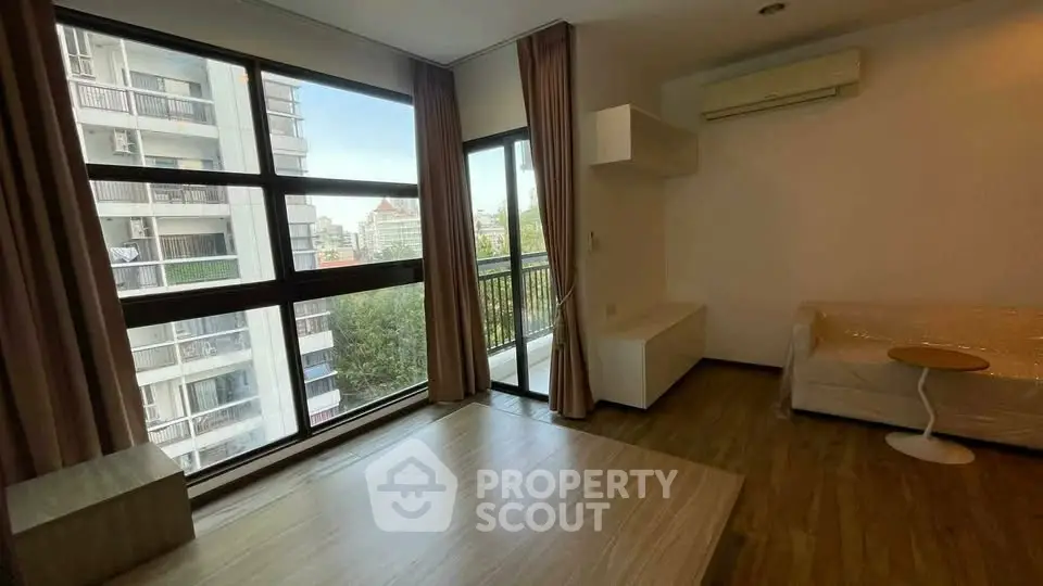 Spacious living room with large windows and balcony view in modern apartment.