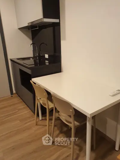 Modern compact kitchen with sleek black appliances and cozy dining area.