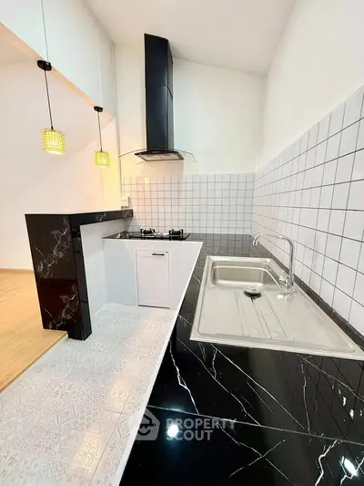 Modern kitchen with sleek black marble countertops and stylish pendant lighting