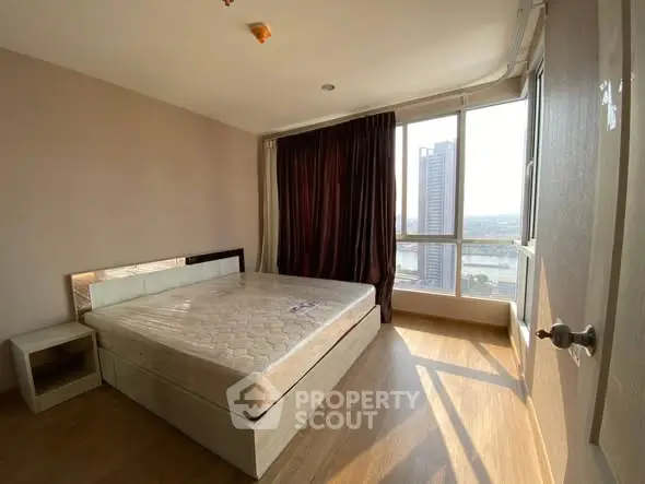 Spacious bedroom with large window offering stunning city views and natural light.
