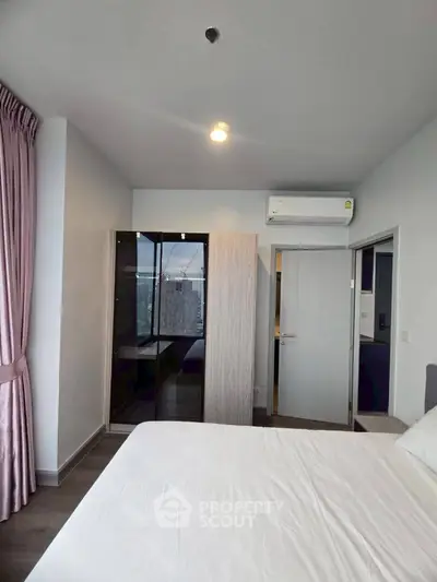 Modern bedroom with sleek design, featuring large window and air conditioning unit.