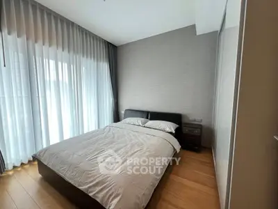 Modern bedroom with elegant decor and floor-to-ceiling windows for natural light.