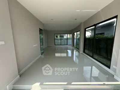 Spacious modern living room with large windows and glossy tiled floors