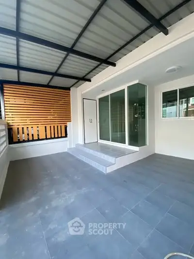 Modern home entrance with sleek glass doors and spacious tiled patio area.