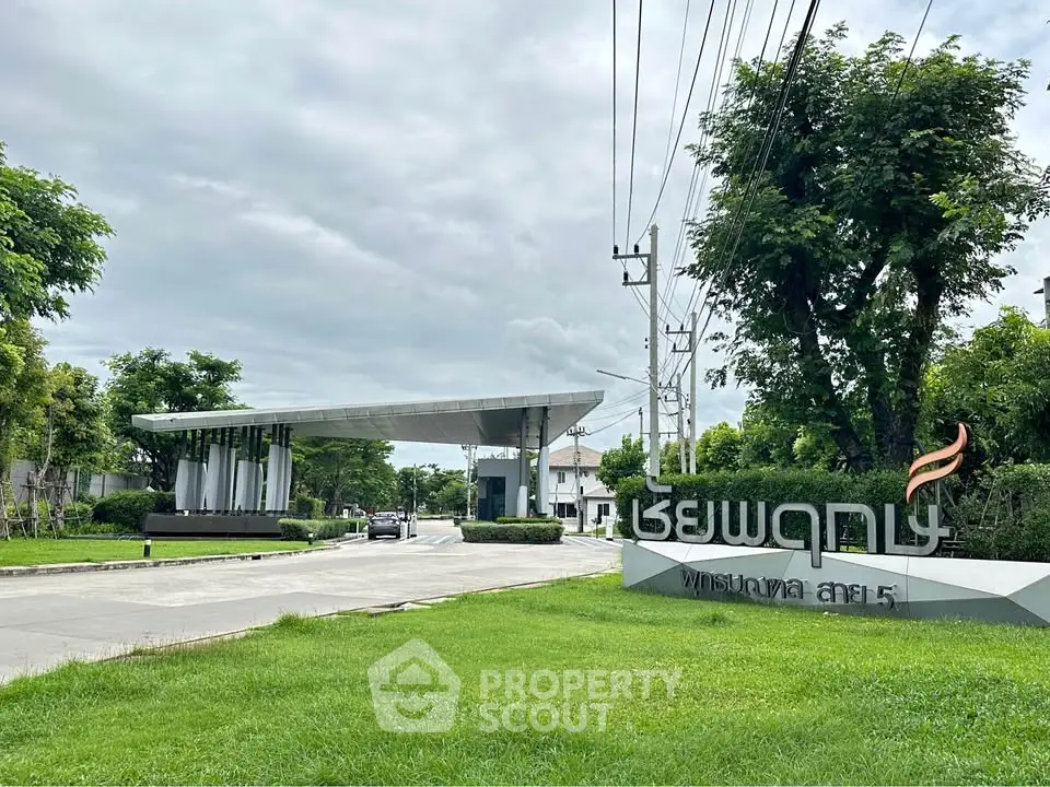 Modern residential entrance with lush greenery and sleek design, showcasing a welcoming neighborhood.