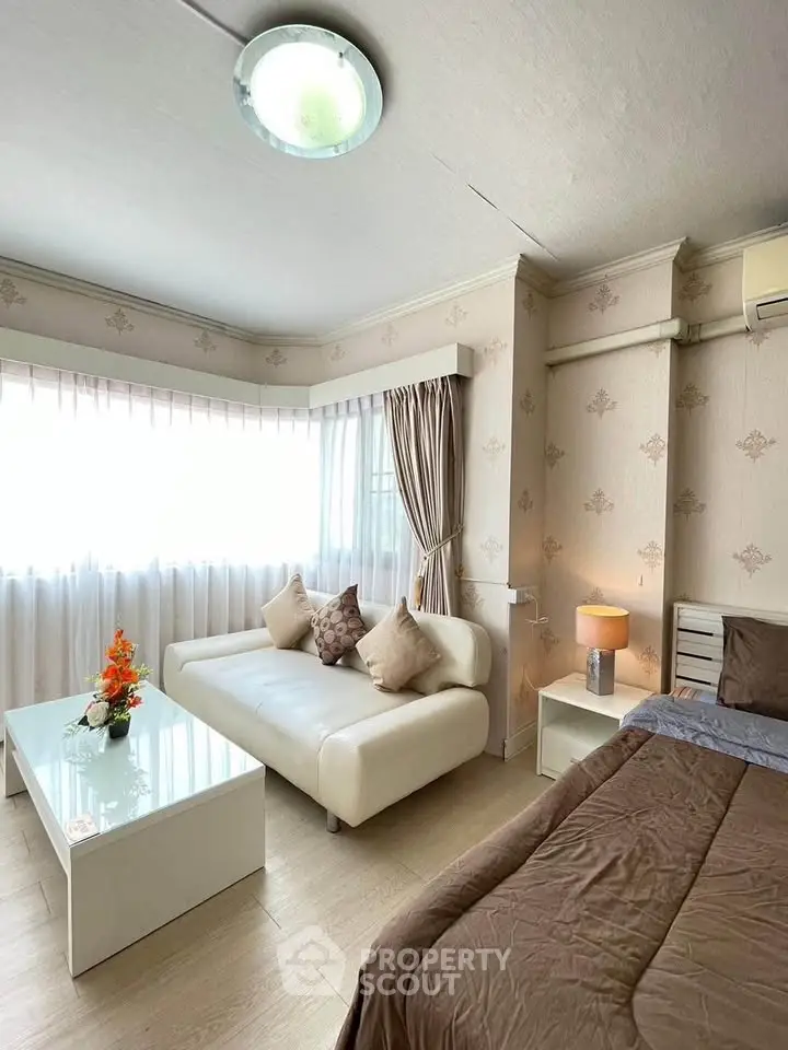 Cozy bedroom with elegant decor and natural light, featuring a stylish sofa and modern furnishings.