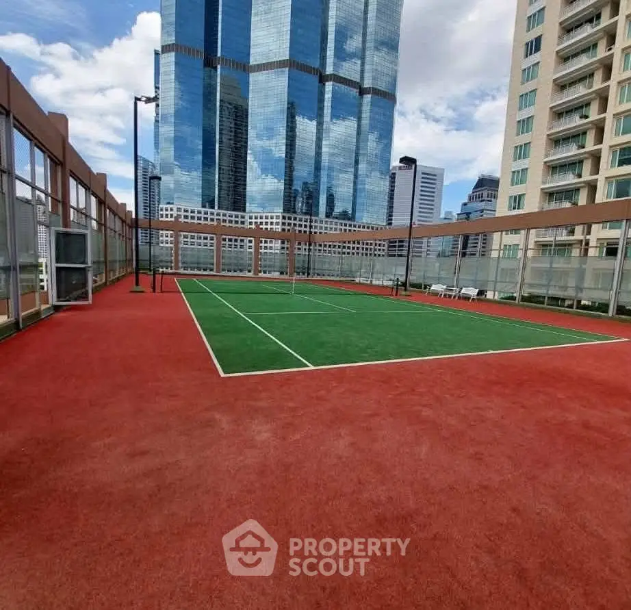Stunning rooftop tennis court with city skyline views in a modern high-rise building.