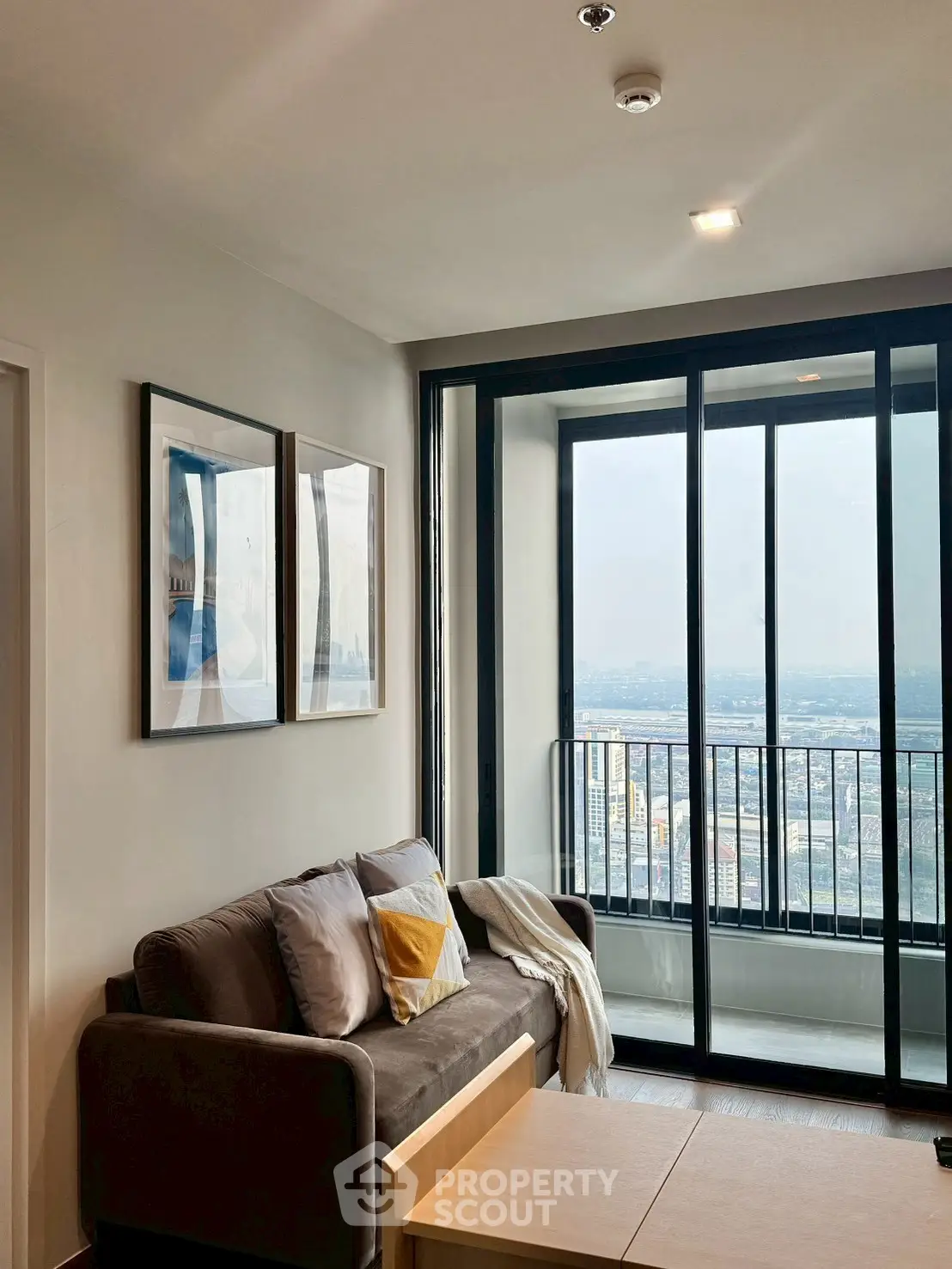 Modern living room with large windows offering stunning city views and cozy seating area.