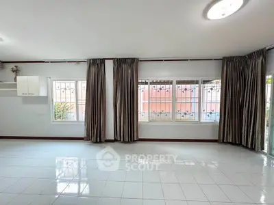 Spacious living room with large windows and elegant curtains, perfect for natural light and modern living.