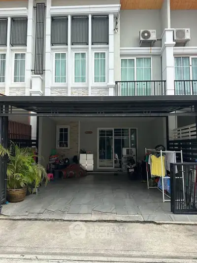 Modern townhouse exterior with covered parking and balcony, showcasing contemporary design and urban living.