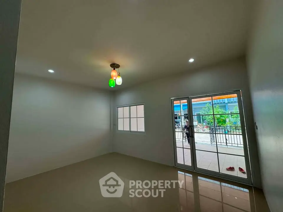 Spacious empty room with glossy floor and colorful ceiling lights, featuring large windows and sliding glass doors.