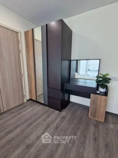 Modern bedroom corner with sleek wardrobe and vanity, featuring wood accents and a potted plant.