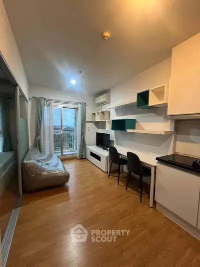 Modern living room with stylish furniture and large window offering natural light and city view.