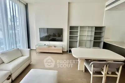 Modern living room with sleek furniture and large TV, featuring floor-to-ceiling windows for natural light.