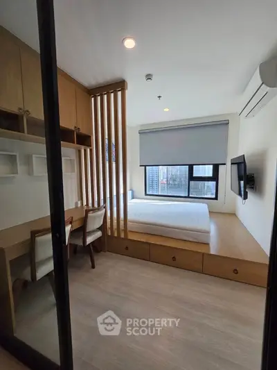 Modern bedroom with platform bed, built-in desk, and large window offering city views.