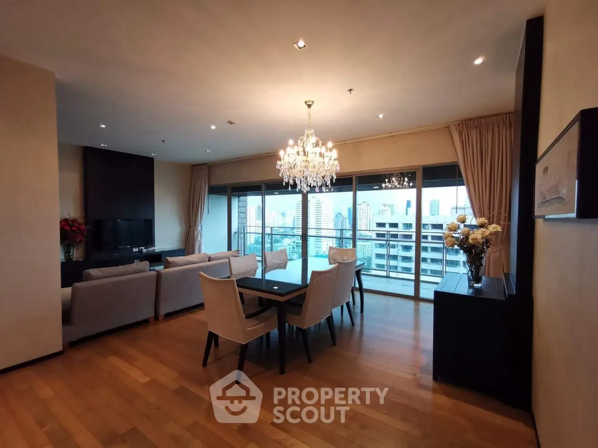 Luxurious living room with elegant chandelier and stunning city view from balcony.