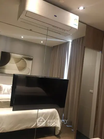 Modern bedroom with sleek design, featuring a wall-mounted TV and air conditioning unit.