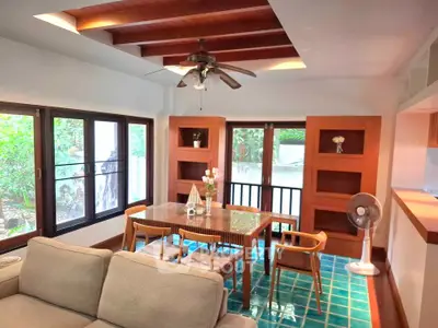 Charming living room with wooden ceiling beams, cozy seating, and vibrant blue tile flooring.