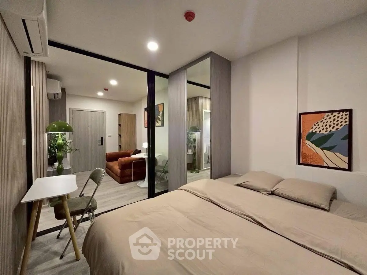 Modern bedroom with stylish decor and open layout leading to living area.