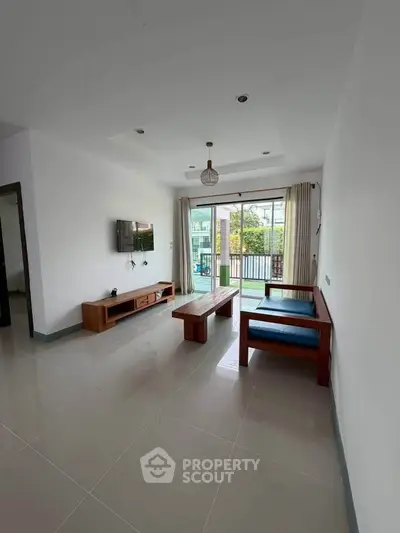 Spacious living room with modern furniture and large windows opening to a balcony with a view.
