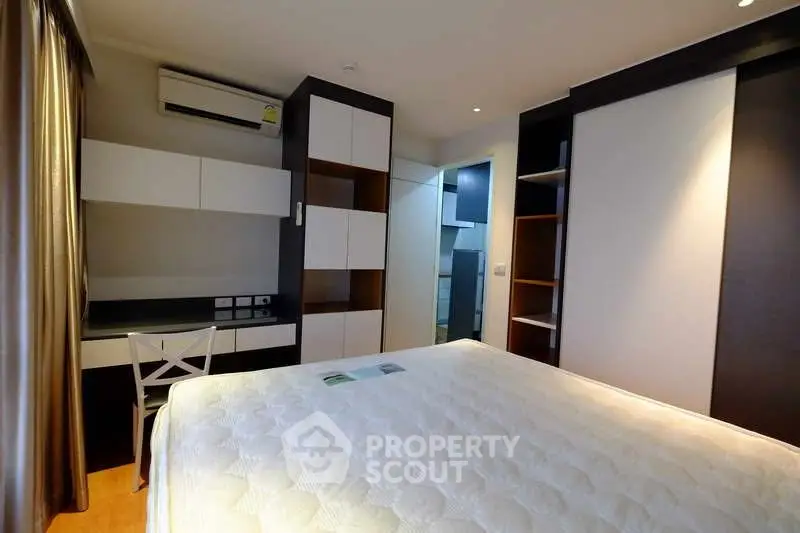 Modern bedroom with built-in storage and air conditioning in a stylish apartment.
