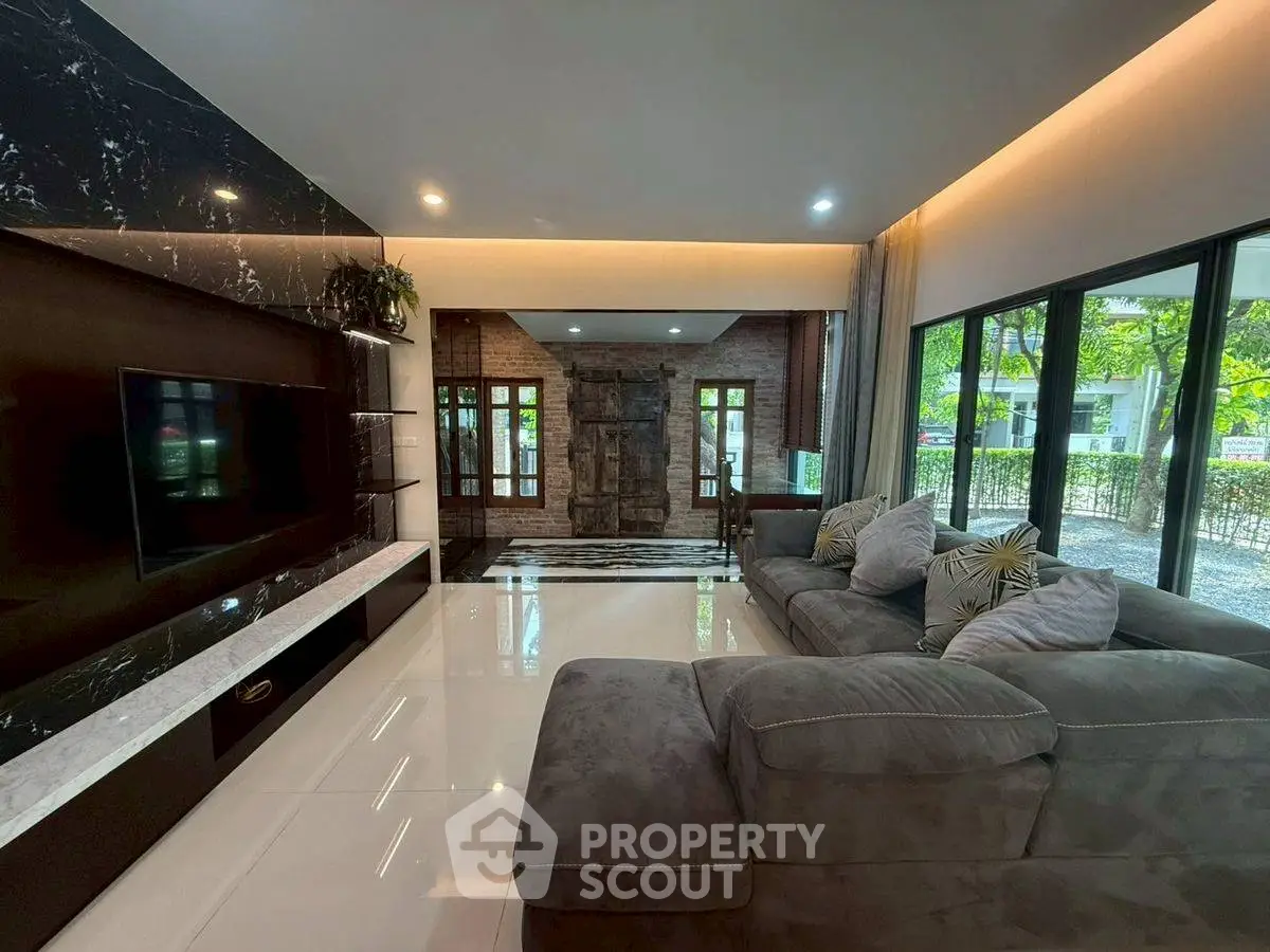 Luxurious living room with modern decor and large windows offering a serene garden view.