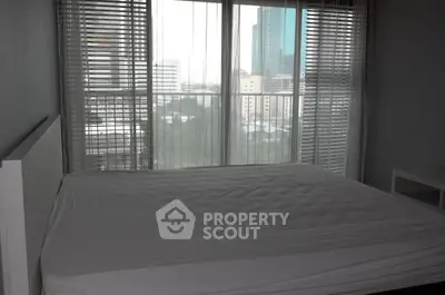 Spacious bedroom with large windows offering a stunning city view, perfect for urban living.
