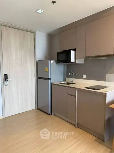 Modern compact kitchen with sleek cabinetry and integrated appliances in a stylish apartment.