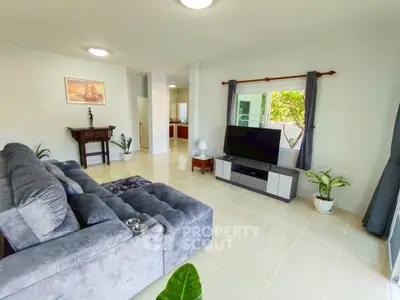 Spacious living room with modern decor and large TV, perfect for relaxation.