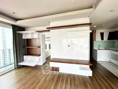 Modern open-layout apartment with sleek wooden flooring and built-in shelving near a balcony.