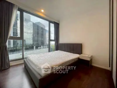 Modern bedroom with large windows and city view in a stylish apartment.