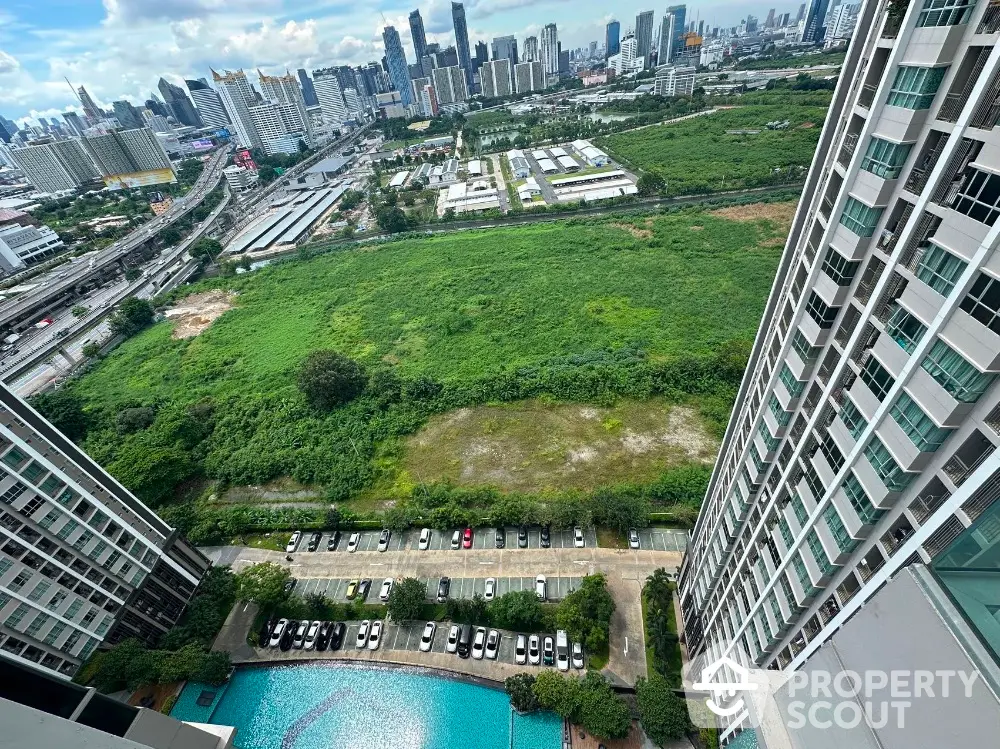 Stunning high-rise view overlooking cityscape and lush greenery with pool and parking below.