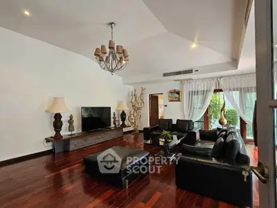 Luxurious living room with elegant decor and hardwood floors, featuring a stylish chandelier and leather seating.