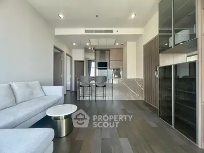 Modern living room with sleek design and open kitchen layout, featuring elegant furniture and stylish decor.