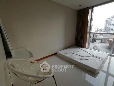 Spacious bedroom with large window and minimalist decor in modern apartment.