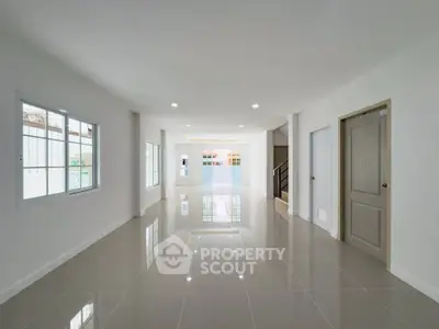 Spacious modern living room with glossy tiled floors and ample natural light.