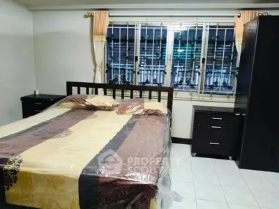 Spacious bedroom with large window and modern furnishings in a cozy home.