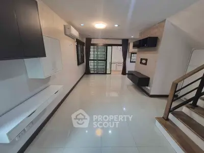Spacious modern living room with sleek design and staircase, perfect for contemporary living.