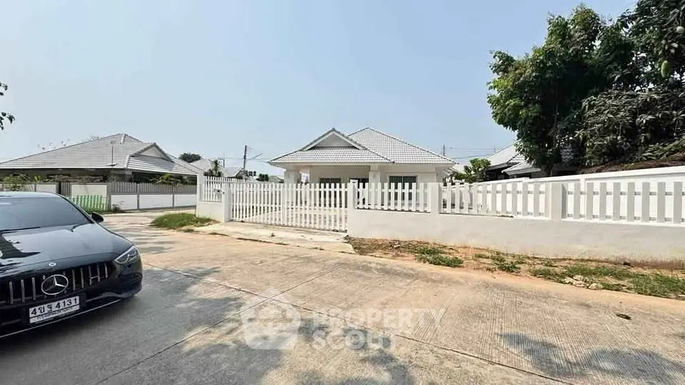 Charming suburban house with white picket fence and driveway in a peaceful neighborhood.