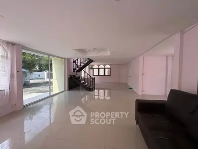Spacious living room with large windows and elegant staircase in modern home