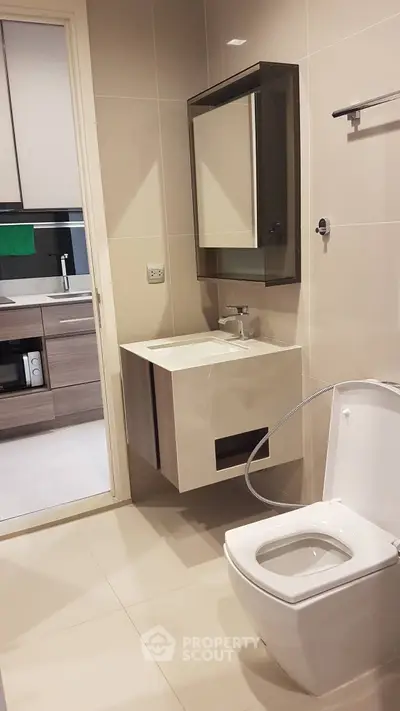 Modern bathroom with sleek fixtures and a view into a contemporary kitchen.