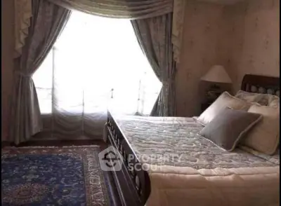 Cozy bedroom with elegant drapes and plush bedding, perfect for relaxation.