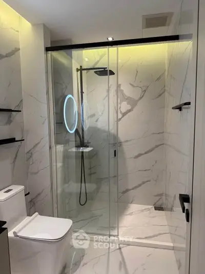 Luxurious modern bathroom with marble tiles and sleek glass shower enclosure.