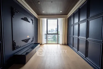 Luxurious empty room with elegant paneling and large window offering city views.