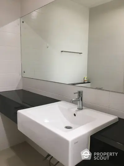 Modern bathroom with sleek white sink and large mirror