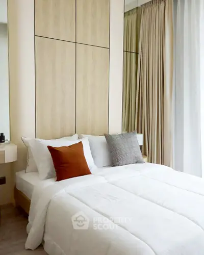 Modern bedroom with cozy bedding and elegant wood paneling, featuring floor-to-ceiling curtains for a serene ambiance.