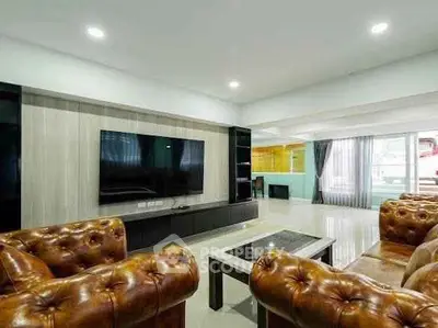 Luxurious living room with leather sofas and large TV, perfect for relaxation and entertainment.