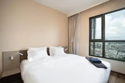 Modern bedroom with city view and large window, featuring a comfortable bed and elegant decor.